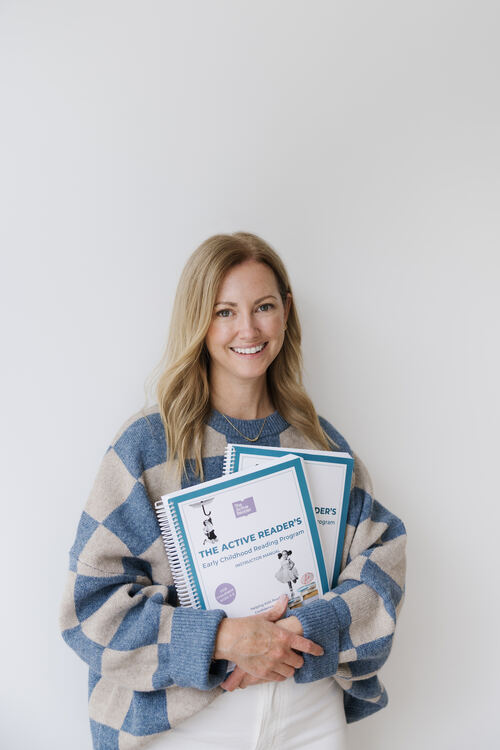 Rebecca, founder of The Active Reader, holding instructional manuals